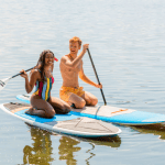 a woman and man on paddle boards on the lake